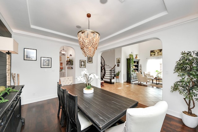 19910 Standing Cypress Dr, Spring, TX 77379 - dining room featuring a raised ceiling, arched walkways, a chandelier, stairway, and baseboards