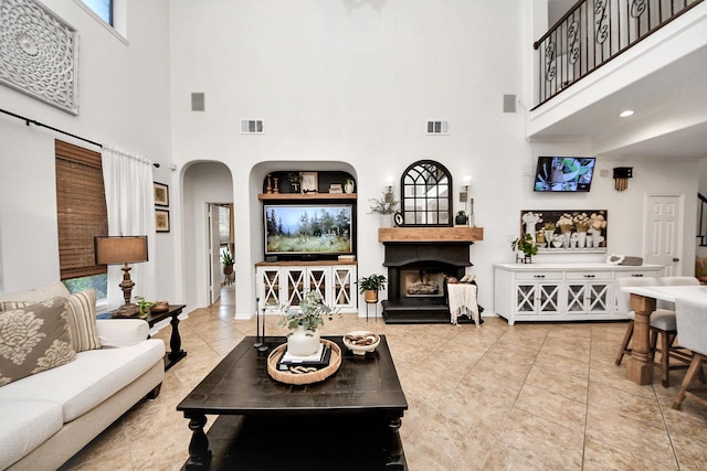 19910 Standing Cypress Dr, Spring, TX 77379 - living room with a towering ceiling, a fireplace with raised hearth, arched walkways, and tile patterned flooring