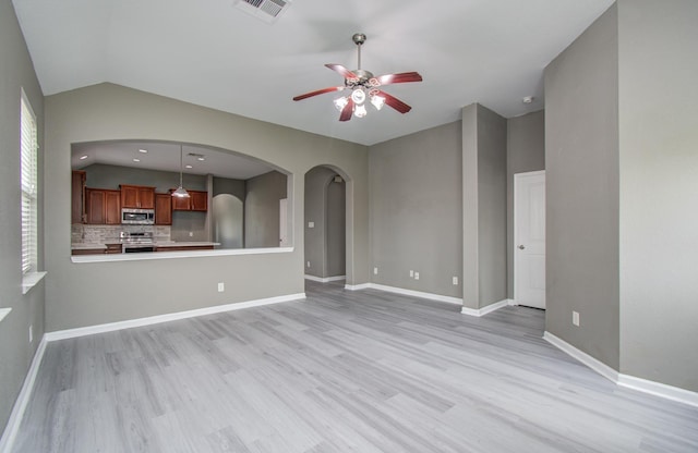 15303 Arnold, Baytown, TX 77523 - unfurnished living room with a ceiling fan, light wood finished floors, lofted ceiling, arched walkways, and baseboards