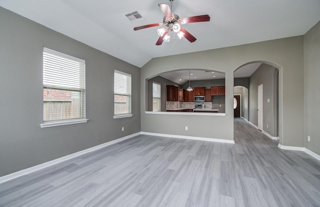 15303 Arnold, Baytown, TX 77523 - unfurnished living room with light wood finished floors, ceiling fan, baseboards, lofted ceiling, and arched walkways
