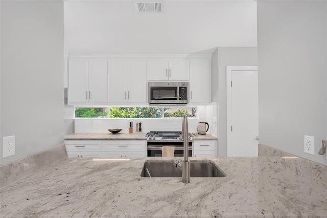668 Lester St, Houston, TX 77007 - kitchen featuring stainless steel appliances, light stone counters, decorative backsplash, and white cabinets