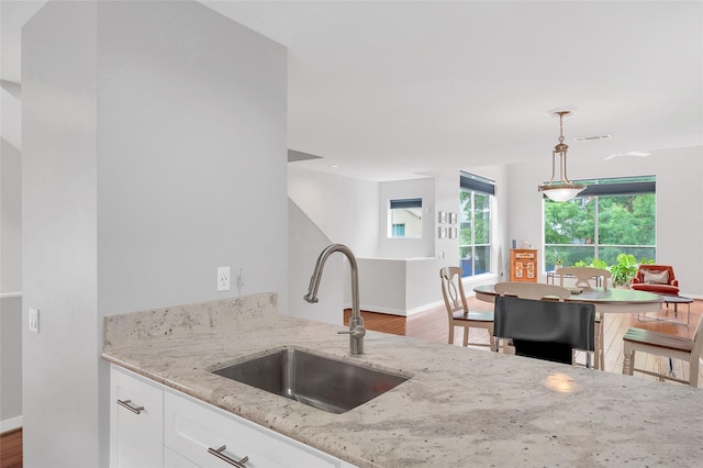 668 Lester St, Houston, TX 77007 - kitchen with a sink, light stone counters, white cabinets, decorative light fixtures, and baseboards