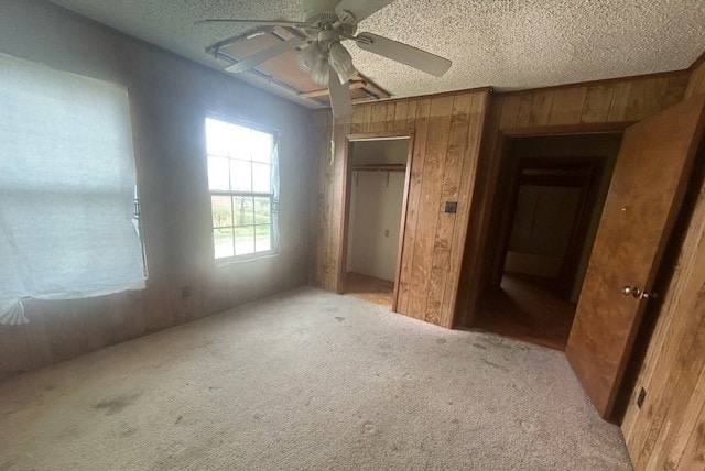 501 S 15th St, Seadrift, TX 77983 - unfurnished bedroom featuring wood walls, carpet floors, a textured ceiling, a closet, and a ceiling fan