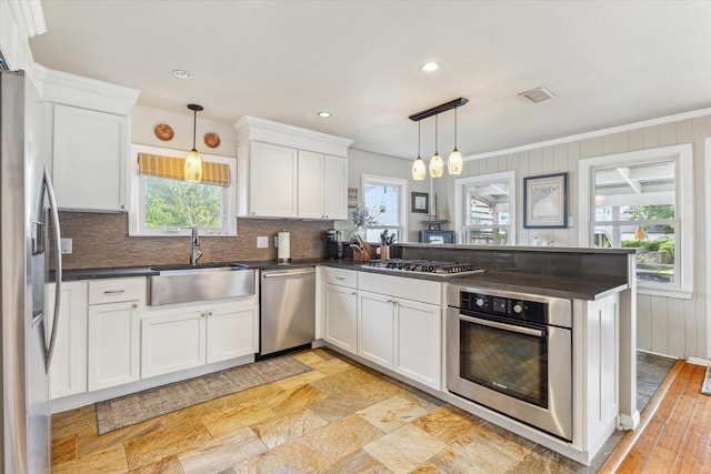 210 Queen Rd, Clear Lake Shores, TX 77565 - kitchen with stainless steel appliances, a sink, dark countertops, a peninsula, and decorative backsplash