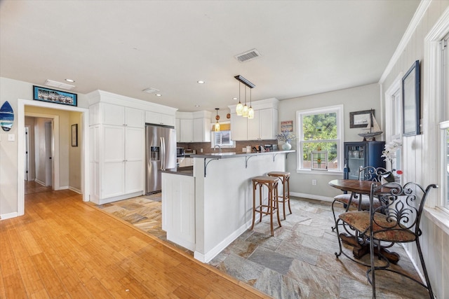 210 Queen Rd, Clear Lake Shores, TX 77565 - kitchen featuring stainless steel fridge, a breakfast bar area, white cabinetry, baseboards, and a peninsula