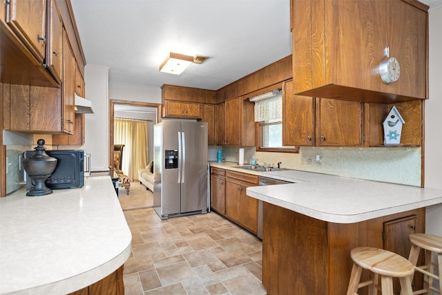 111 Ann St, Crockett, TX 75835 - kitchen with stainless steel appliances, brown cabinetry, a peninsula, and light countertops