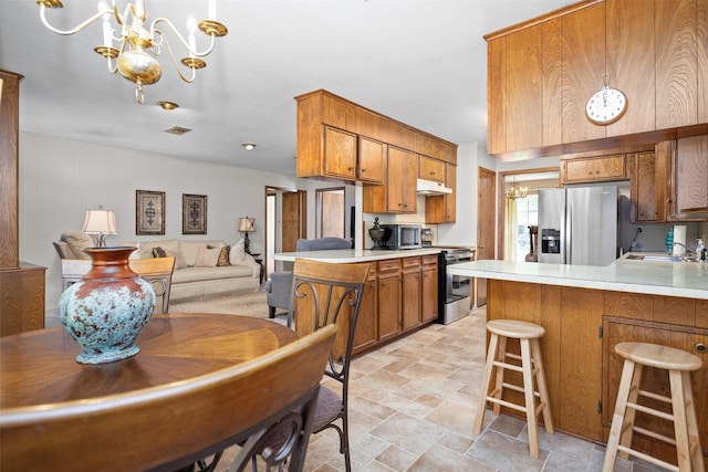 111 Ann St, Crockett, TX 75835 - kitchen featuring appliances with stainless steel finishes, a peninsula, brown cabinets, and light stone finish flooring