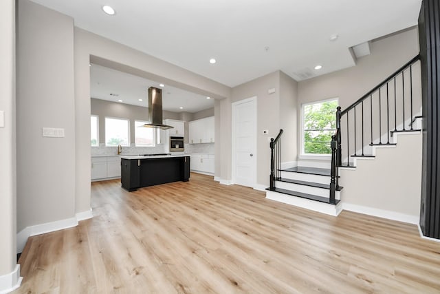 3913 Griggs Rd, Houston, TX 77021 - unfurnished living room featuring light wood-type flooring, stairway, a sink, baseboards, and recessed lighting