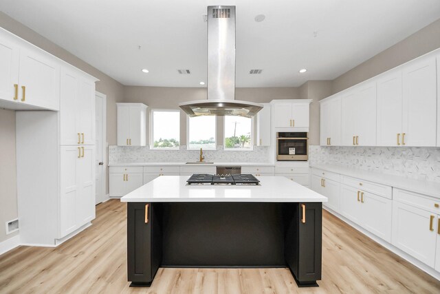 3913 Griggs Rd, Houston, TX 77021 - kitchen with stainless steel appliances, island exhaust hood, a kitchen island, backsplash, and white cabinets