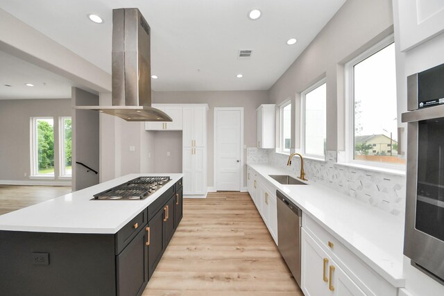 3913 Griggs Rd, Houston, TX 77021 - kitchen featuring island exhaust hood, appliances with stainless steel finishes, a sink, white cabinetry, and light countertops