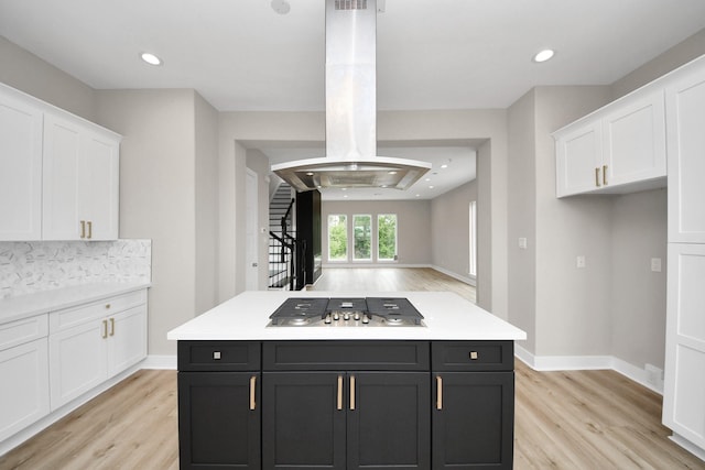 3913 Griggs Rd, Houston, TX 77021 - kitchen featuring stainless steel gas stovetop, island exhaust hood, white cabinetry, light wood-style flooring, and dark cabinetry