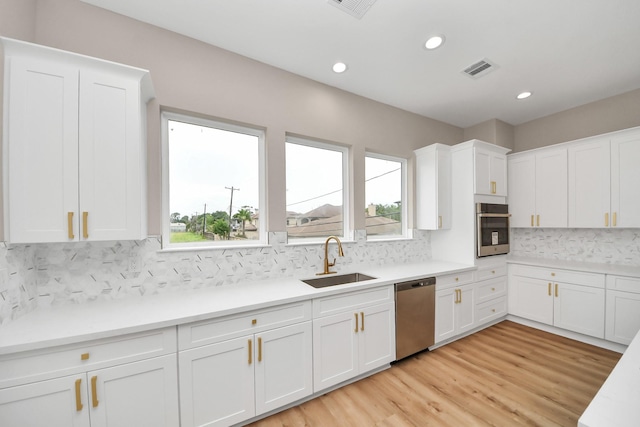 3913 Griggs Rd, Houston, TX 77021 - kitchen with stainless steel appliances, a sink, white cabinets, backsplash, and recessed lighting