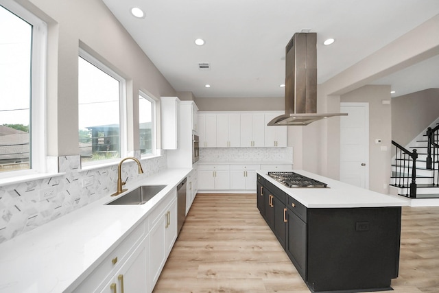 3913 Griggs Rd, Houston, TX 77021 - kitchen with island exhaust hood, a sink, stainless steel appliances, dark cabinetry, and white cabinets