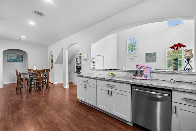 9307 Seeker St, Houston, TX 77028 - kitchen with stainless steel dishwasher, arched walkways, light stone counters, dark wood-style flooring, and recessed lighting