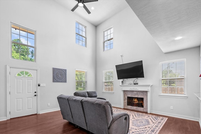 9307 Seeker St, Houston, TX 77028 - living room with a tiled fireplace, a ceiling fan, dark wood-style floors, healthy amount of natural light, and a high ceiling