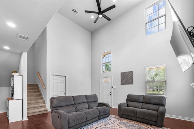 9307 Seeker St, Houston, TX 77028 - living room featuring a towering ceiling, dark wood finished floors, ceiling fan, baseboards, and stairs