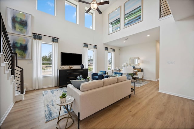 16800 Needlepoint Dr, Conroe, TX 77302 - living room with light wood finished floors, stairway, ceiling fan, baseboards, and a towering ceiling