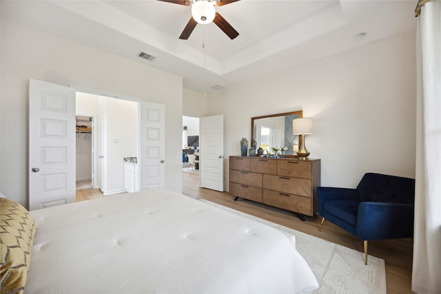 16800 Needlepoint Dr, Conroe, TX 77302 - bedroom featuring wood finished floors, a raised ceiling, and a ceiling fan