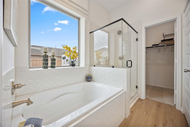 16800 Needlepoint Dr, Conroe, TX 77302 - bathroom with a bath, a stall shower, a walk in closet, and wood finished floors