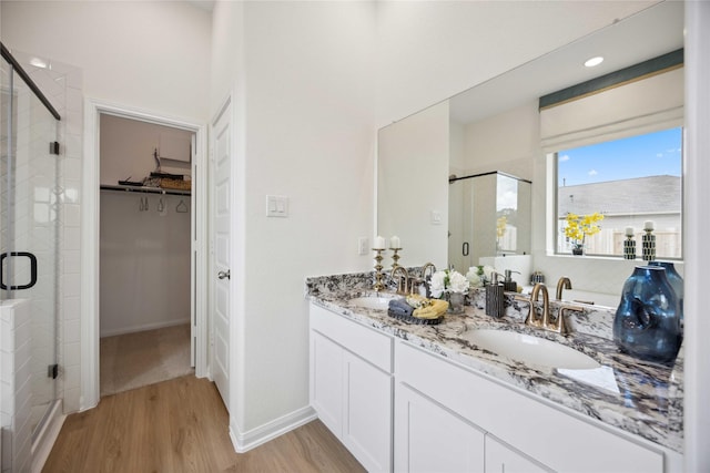 16800 Needlepoint Dr, Conroe, TX 77302 - bathroom with a shower stall, a walk in closet, wood finished floors, double vanity, and baseboards