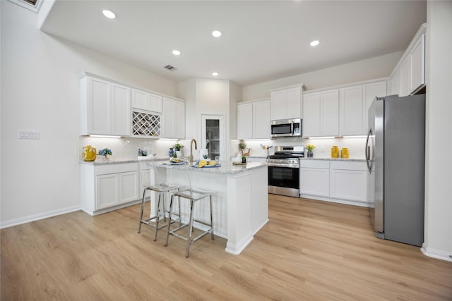 16800 Needlepoint Dr, Conroe, TX 77302 - kitchen with appliances with stainless steel finishes, tasteful backsplash, a center island, light wood-type flooring, and recessed lighting