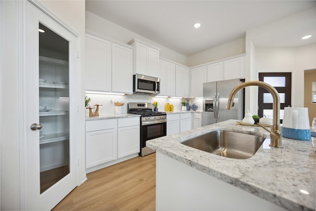 16800 Needlepoint Dr, Conroe, TX 77302 - kitchen featuring stainless steel appliances, a sink, white cabinets, tasteful backsplash, and recessed lighting