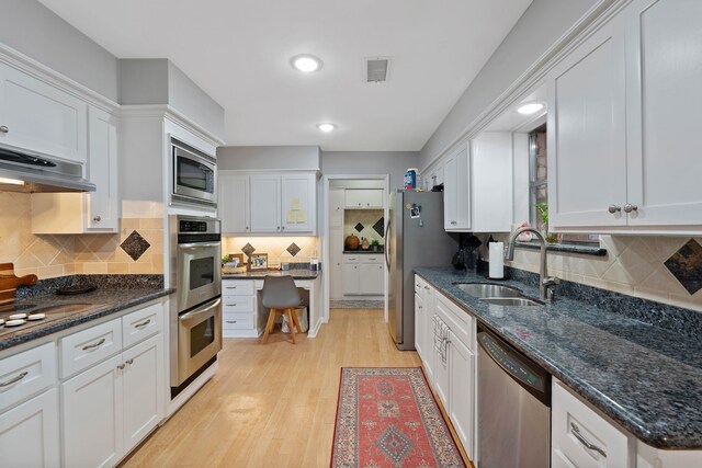 2828 S Logrun Cir, The Woodlands, TX 77380 - kitchen featuring stainless steel appliances, a sink, white cabinets, decorative backsplash, and recessed lighting