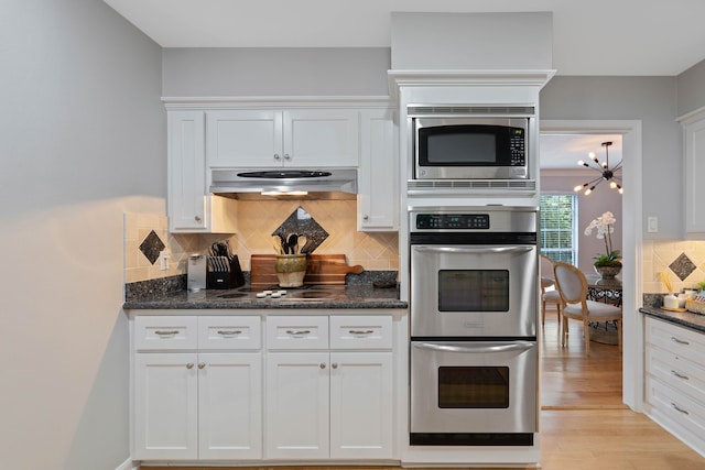 2828 S Logrun Cir, The Woodlands, TX 77380 - kitchen featuring under cabinet range hood, appliances with stainless steel finishes, white cabinets, backsplash, and light wood finished floors