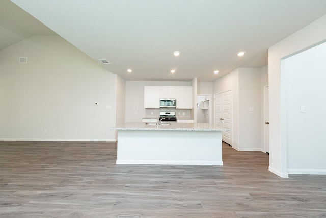 13228 Musky Dr, Conroe, TX 77384 - kitchen featuring stainless steel microwave, stove, white cabinetry, light wood finished floors, and recessed lighting