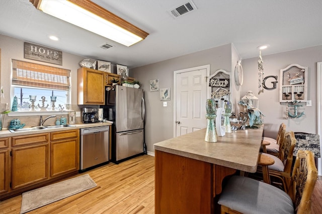 986 Tuna Dr, Crystal Beach, TX 77650 - kitchen with appliances with stainless steel finishes, a sink, a kitchen breakfast bar, light countertops, and light wood-style flooring