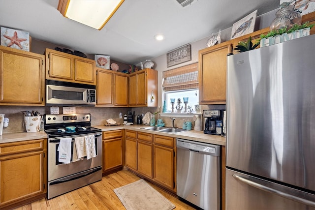 986 Tuna Dr, Crystal Beach, TX 77650 - kitchen with appliances with stainless steel finishes, a sink, light countertops, light wood-style floors, and decorative backsplash