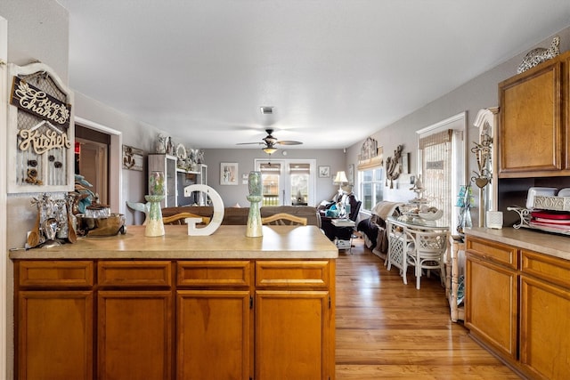 986 Tuna Dr, Crystal Beach, TX 77650 - kitchen featuring a ceiling fan, open floor plan, light wood-type flooring, light countertops, and brown cabinets