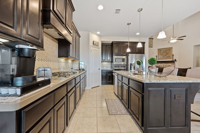 19823 Sonterra Ln, Richmond, TX 77407 - kitchen featuring a sink, appliances with stainless steel finishes, dark brown cabinetry, decorative backsplash, and pendant lighting