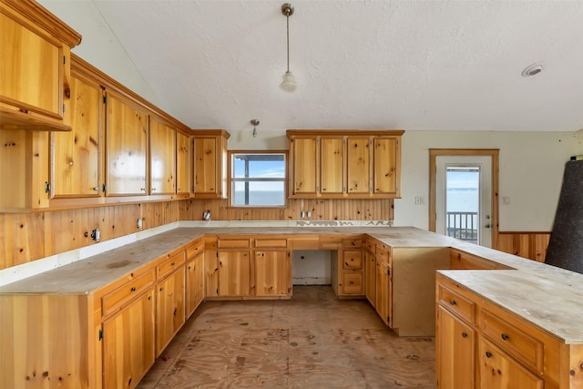 245 Bridgewater, Onalaska, TX 77360 - kitchen featuring a peninsula, light countertops, pendant lighting, a textured ceiling, and a wainscoted wall