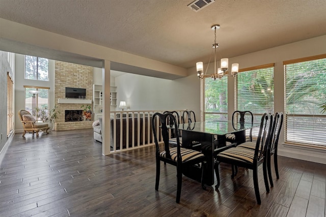 52 S Havenridge Dr, The Woodlands, TX 77381 - dining room with a textured ceiling, a chandelier, dark wood-style flooring, a brick fireplace, and baseboards