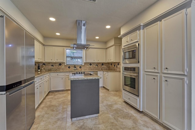 52 S Havenridge Dr, The Woodlands, TX 77381 - kitchen with stainless steel appliances, island exhaust hood, tasteful backsplash, a center island, and light stone countertops