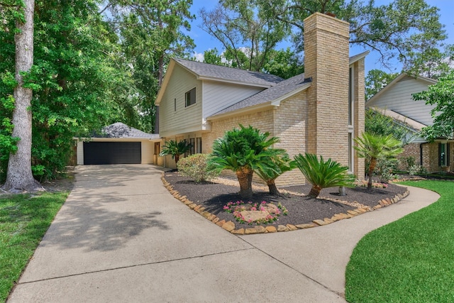 52 S Havenridge Dr, The Woodlands, TX 77381 - view of front of house with brick siding, a chimney, a shingled roof, and driveway
