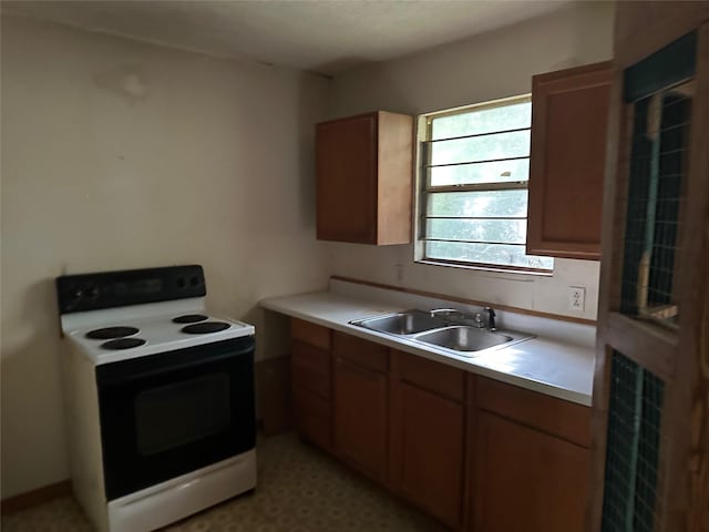 1883 Winding Creek Dr, Trinity, TX 75862 - kitchen with range with electric stovetop, a sink, light countertops, and brown cabinetry