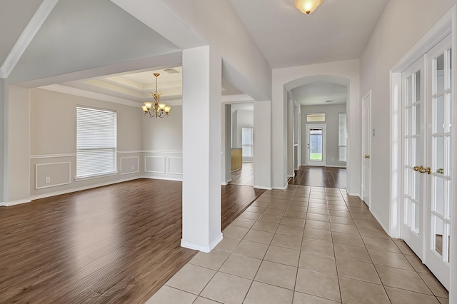9927 Barr Lake Dr, Houston, TX 77095 - entrance foyer featuring arched walkways, light wood-style floors, a chandelier, wainscoting, and a decorative wall