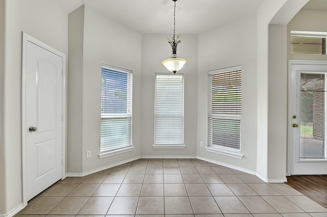 9927 Barr Lake Dr, Houston, TX 77095 - unfurnished dining area featuring light tile patterned flooring, baseboards, and arched walkways