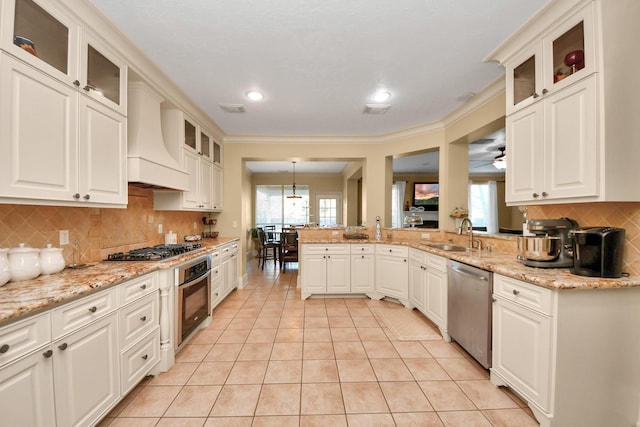 10138 Bayou Manor Ln, Houston, TX 77064 - kitchen featuring appliances with stainless steel finishes, a sink, light tile patterned flooring, premium range hood, and plenty of natural light