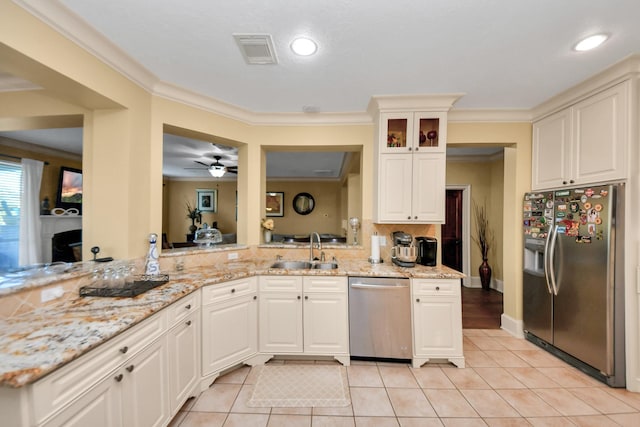 10138 Bayou Manor Ln, Houston, TX 77064 - kitchen featuring appliances with stainless steel finishes, a sink, light tile patterned floors, glass insert cabinets, and light stone counters