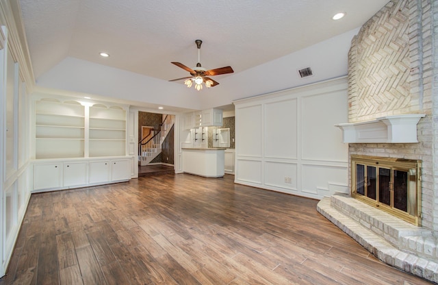5810 Springton Ln, Spring, TX 77379 - unfurnished living room with ceiling fan, vaulted ceiling, stairway, dark wood-style flooring, and a brick fireplace