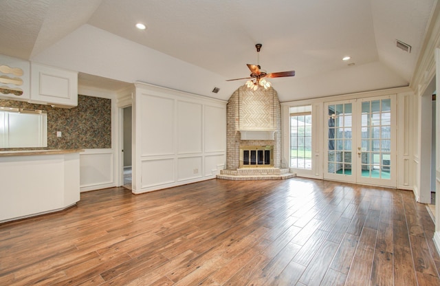5810 Springton Ln, Spring, TX 77379 - unfurnished living room featuring vaulted ceiling, a ceiling fan, wood finished floors, a decorative wall, and a brick fireplace