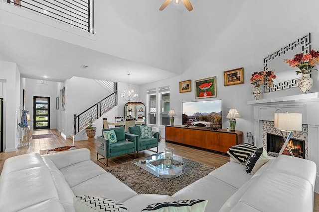 4818 Nodding Thistle Trl, Fulshear, TX 77441 - living room featuring a chandelier, stairs, a high end fireplace, wood finished floors, and a towering ceiling