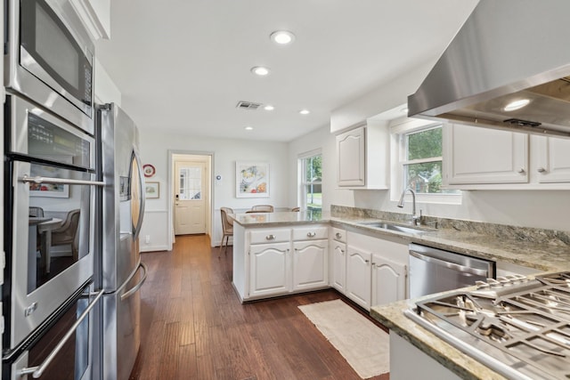 8019 Skyline Dr, Houston, TX 77063 - kitchen with a sink, wall chimney range hood, appliances with stainless steel finishes, a peninsula, and dark wood finished floors