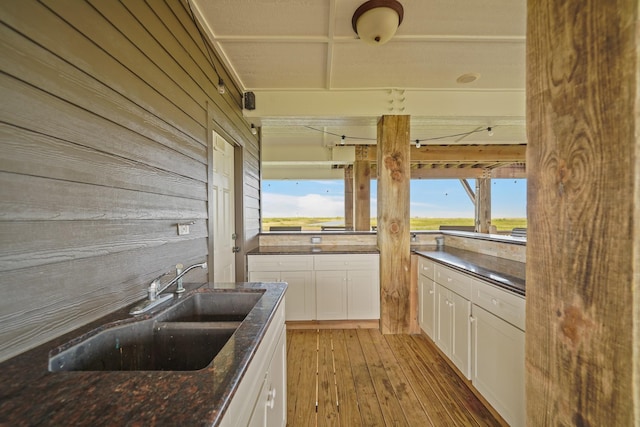 898 Mr G, Crystal Beach, TX 77650 - kitchen featuring a sink, white cabinets, hardwood / wood-style floors, dark stone counters, and wood walls