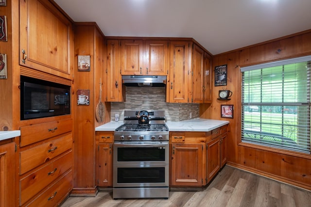 330 N 4th St, Beasley, TX 77417 - kitchen with double oven range, under cabinet range hood, brown cabinets, black microwave, and decorative backsplash