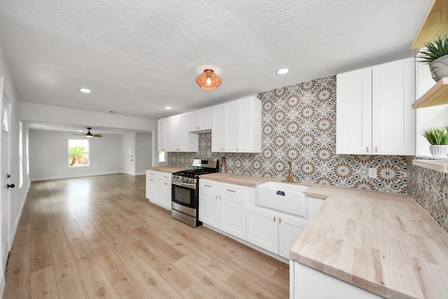 501 Schilling St, Baytown, TX 77520 - kitchen featuring stainless steel gas range, a sink, white cabinetry, wooden counters, and a textured ceiling