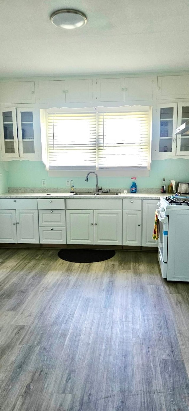 3137 18th St, Port Arthur, TX 77642 - kitchen with white gas range, a sink, white cabinets, and dark wood-type flooring